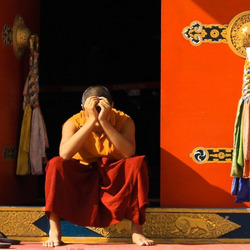 Eine Person mit orangen Klamotten sitzt auf dem Absatz eines Tempels