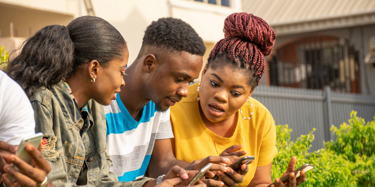 Drei Jugendliche schauen überrascht auf ihre Smartphones.
