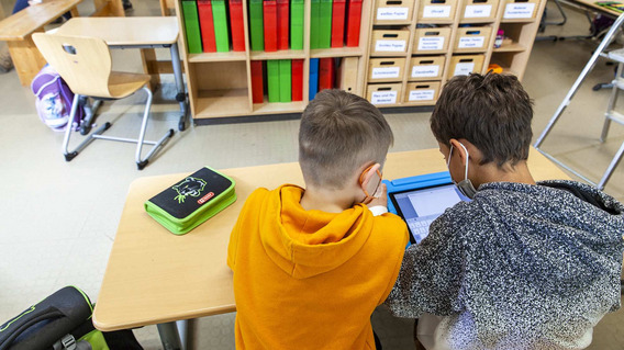 Zwei Schulkinder lernen mit einem Tablet in der Schule.