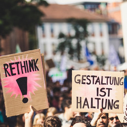 Menschen bei einer Demo halten Schilder mit den Texten "Rethink" und "Gestaltung ist Haltung"