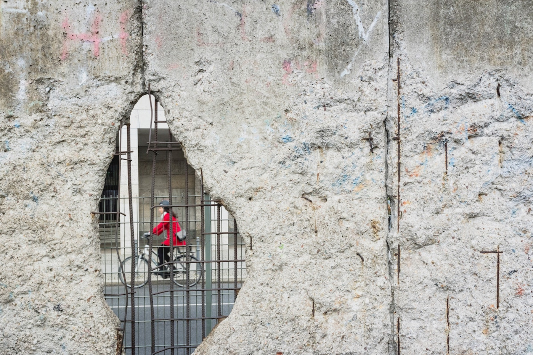 Durch ein Loch in der Mauer sieht man eine Person auf einem Fahrrad.