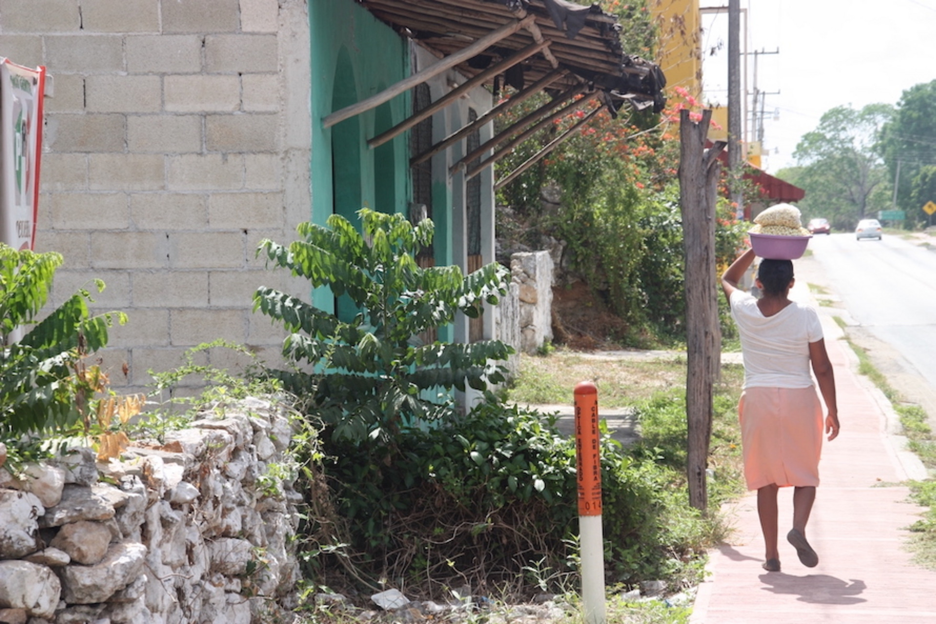Eine Frau läuft durch die Straßen von Mexico und balanciert eine Schüssel mit Essen auf dem Kopf.