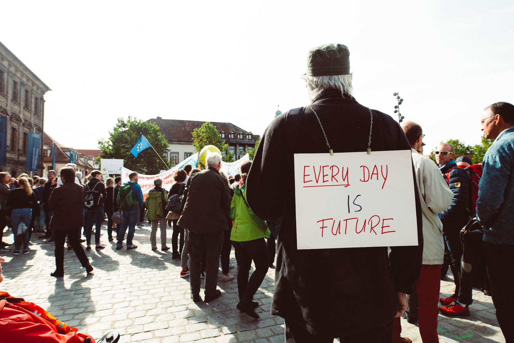 Eine Klima-Demo mit EU-Flaggen auf dem Schlossplatz in Erlangen. Auf dem Schild, das ein Teilnehmer auf dem Rücken trägt, steht "Every Day Is Future".