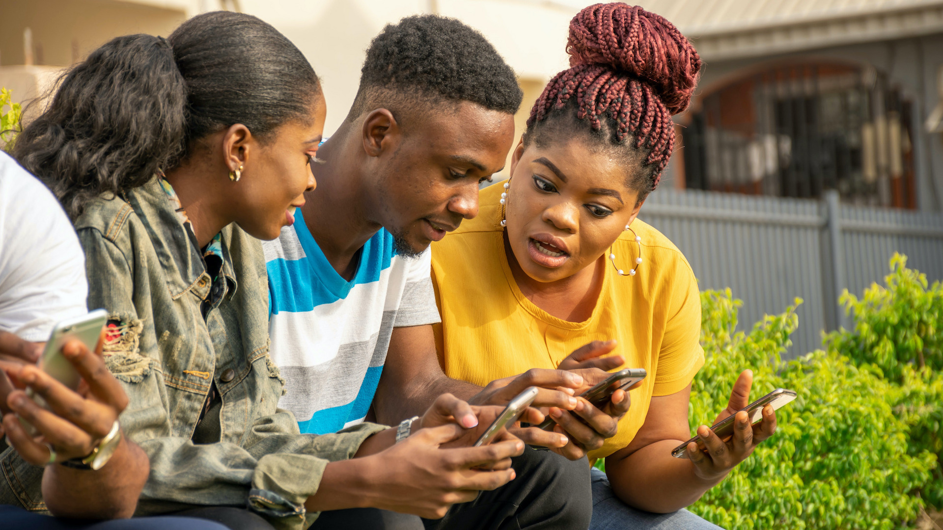 Drei Jugendliche schauen überrascht auf ihre Smartphones.