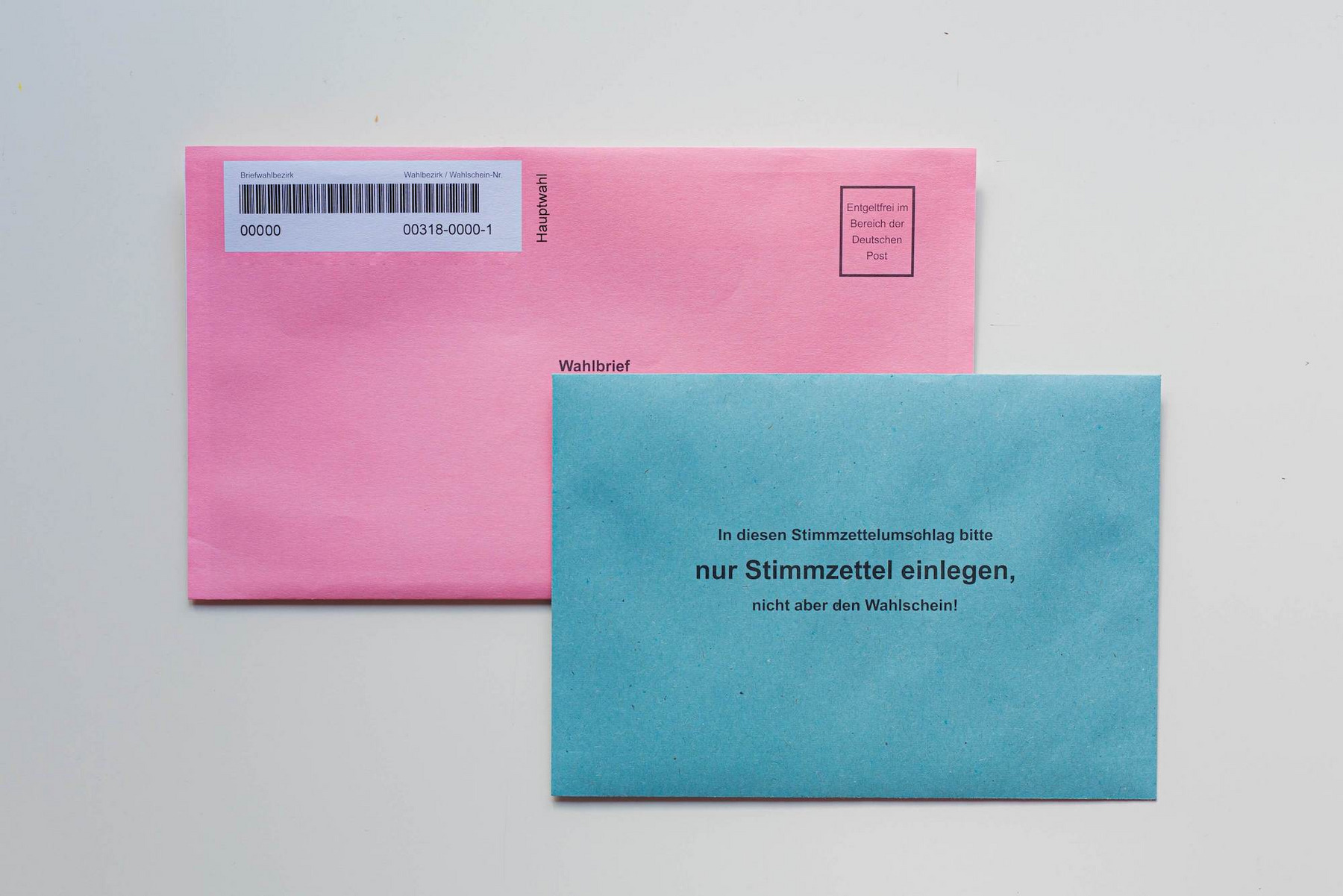 Briefwahlunterlagen: Ein blauer Umschlag liegt auf einem rosaroten Umschlag
