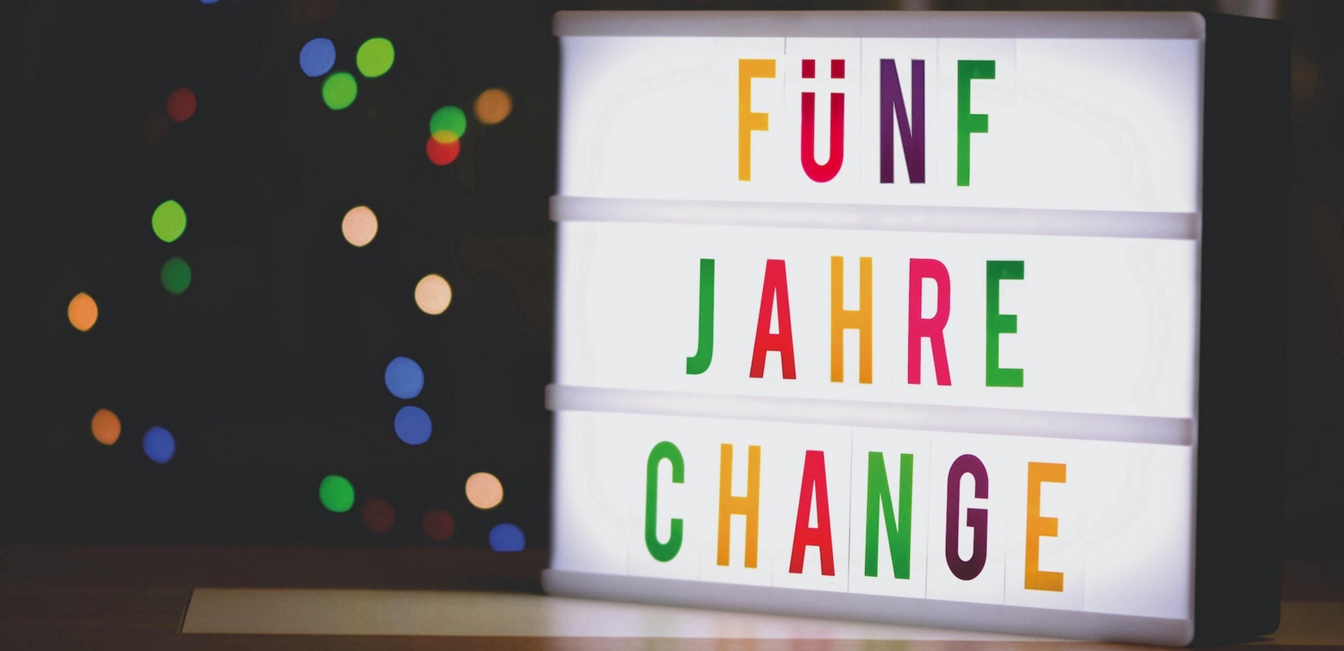 Ein Foto eines Leuchtkastens, in dem mit bunten Buchstaben steht "FÜNF JAHRE CHANGE".