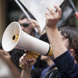Ein junger Mann ruft während einer Demonstration in ein Megafon