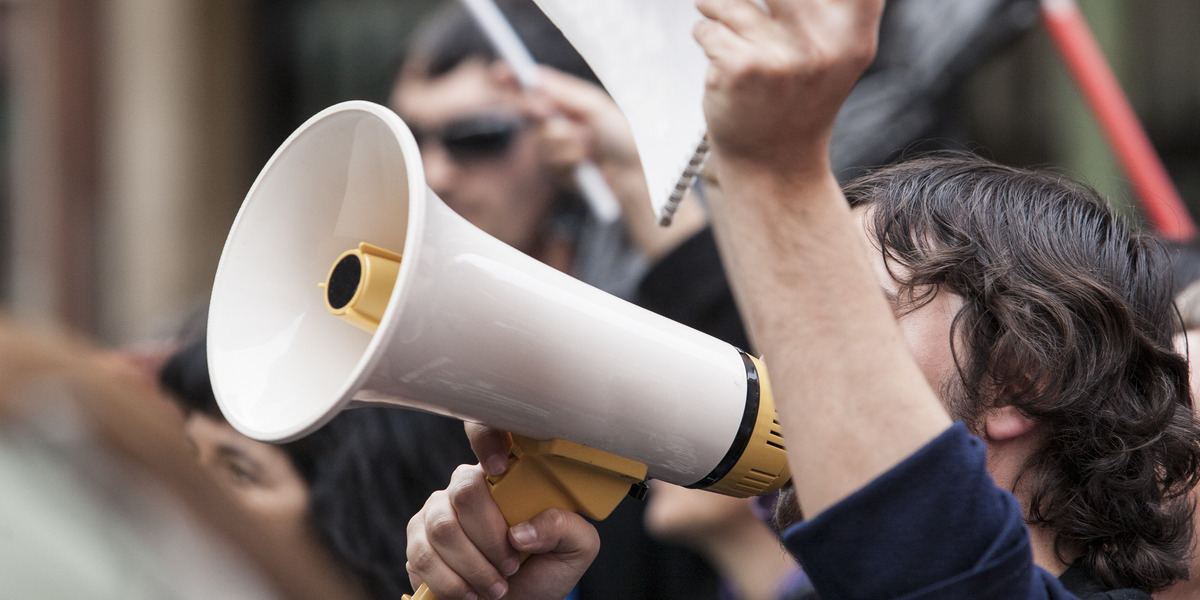 Ein junger Mann ruft während einer Demonstration in ein Megafon