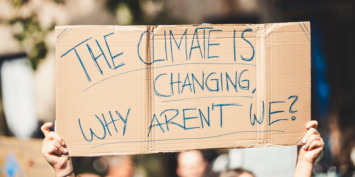 Klimaaktivisten halten ein Plakat hoch: "The climate is changing, why aren't we?"