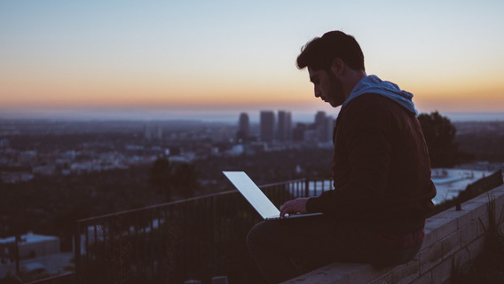 Ein Mann mit Laptop sitzt im Freien und arbeitet