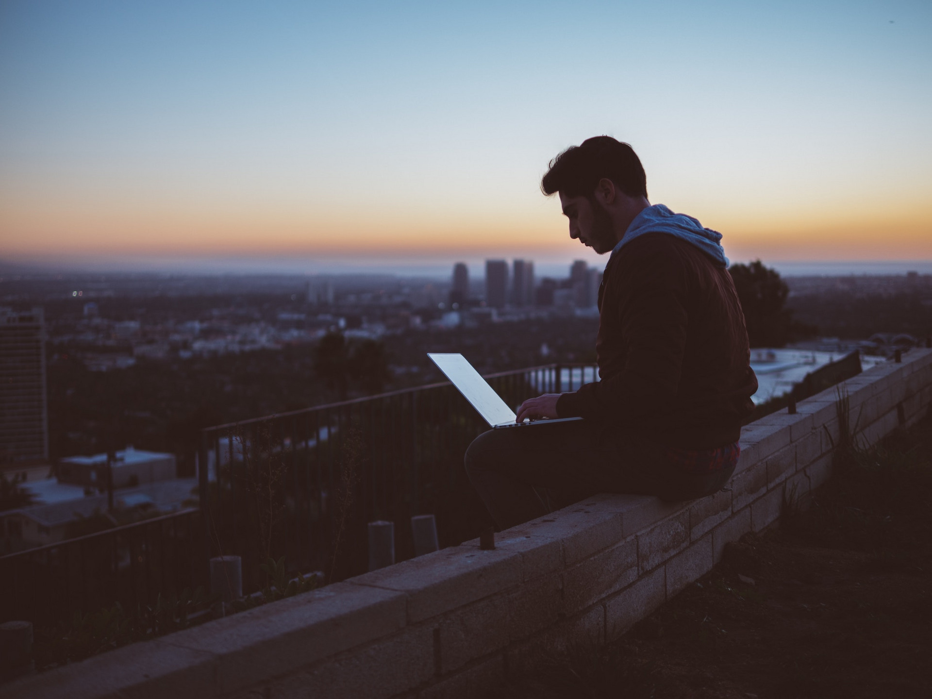 Ein Mann mit Laptop sitzt im Freien und arbeitet