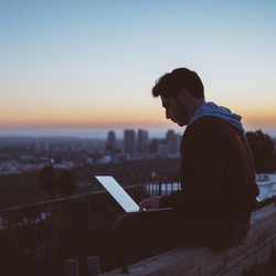Ein Mann mit Laptop sitzt im Freien und arbeitet