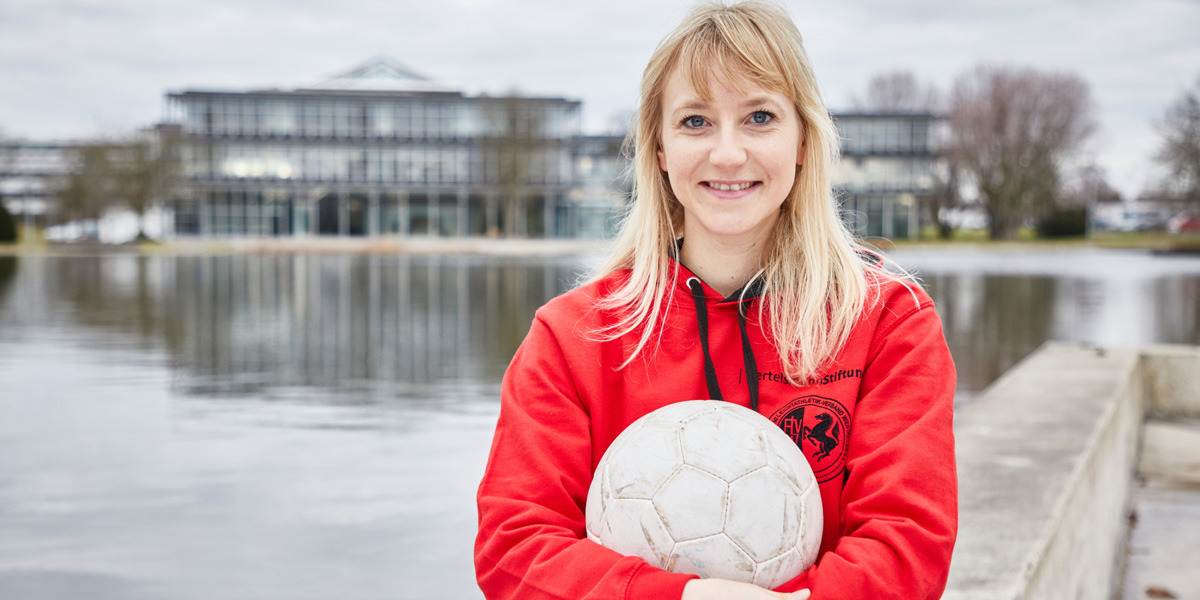 Julia Tegeler mit einem Ball in der Hand vor der Bertelsmann Stiftung