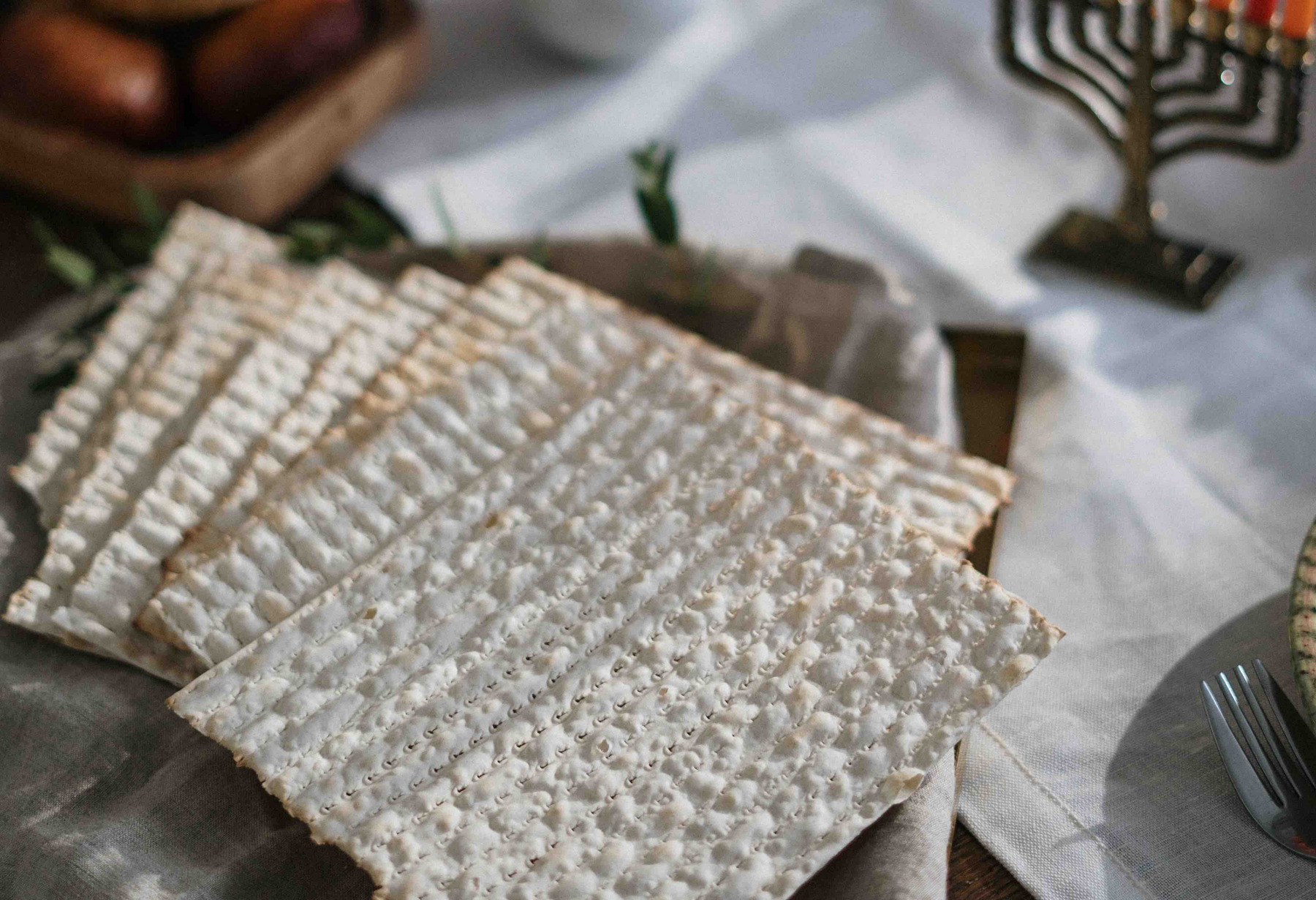 Matzenbrot auf einem gedeckten Tisch, im Hintergrund eine Menorah