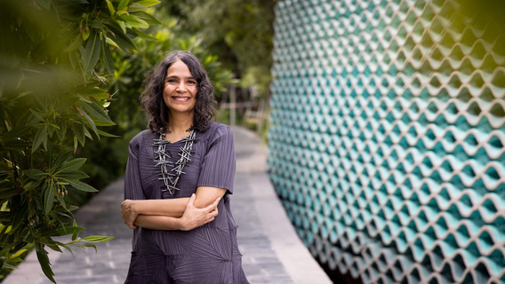 Malavika Jayaram steht in einem Park und lächelt in die Kamera