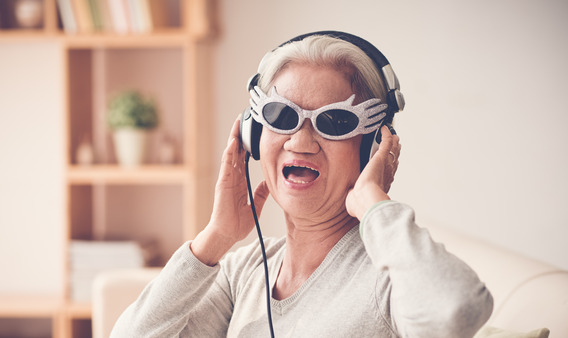 Eine ältere Frau trägt Brille und Kopfhörer und singt.