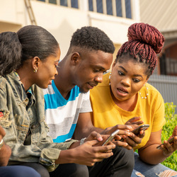 Drei Jugendliche schauen überrascht auf ihre Smartphones.