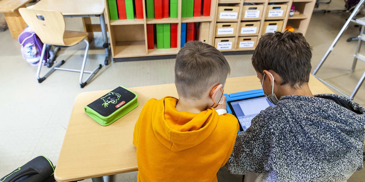 Zwei Schulkinder lernen mit einem Tablet in der Schule.