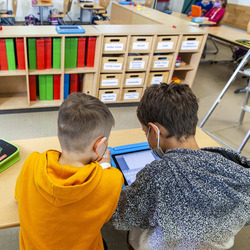 Zwei Schulkinder lernen mit einem Tablet in der Schule.