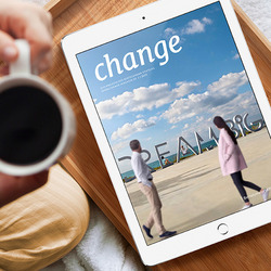 Die neue Ausgabe des change Magazins erscheint auf einem Tablet. Das Gerät liegt auf einem hölzernen Tablett, vor dem eine junge Frau sitzt, die eine Tasse Kaffee in den Händen hält.