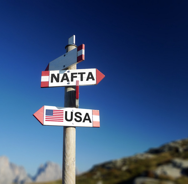 Zwei Schilder mit den Texten "NAFTA" und "USA", die in verschiedenen Richtungen zeigen