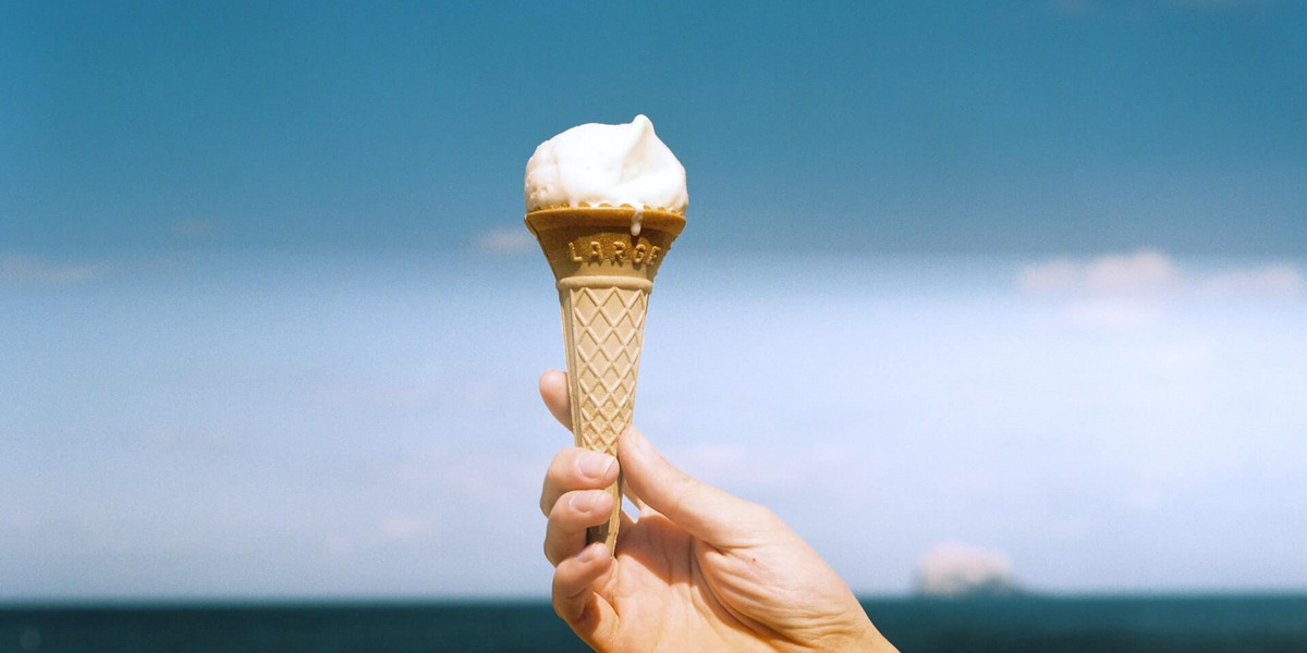 Eine Hand hält eine Eiswaffel Strand.