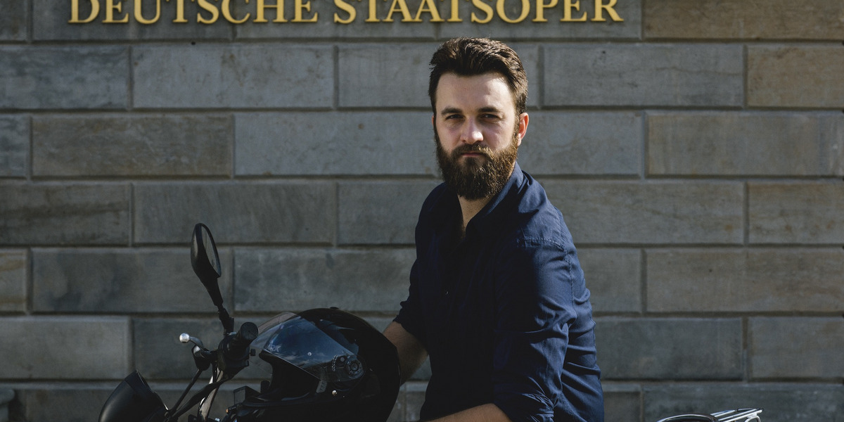 David Oštrek sitzt auf einem Motorrad vor der Staatsoper Berlin