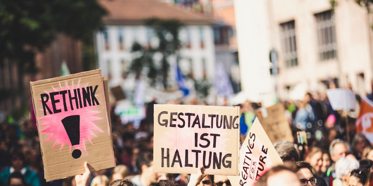 Menschen bei einer Demo halten Schilder mit den Texten "Rethink" und "Gestaltung ist Haltung"