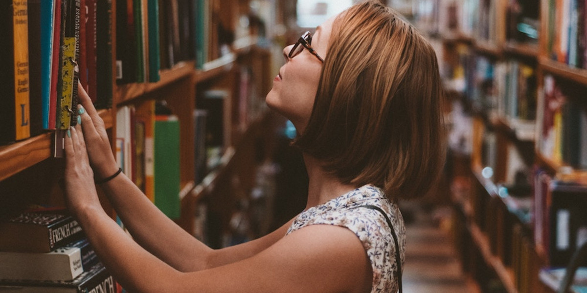 Eine Person steht vor einem Bücherregal.