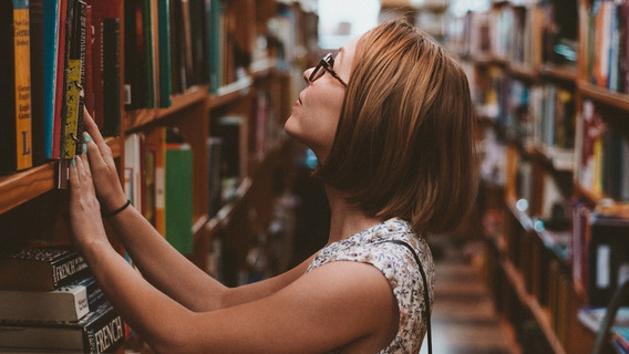 Eine Person steht vor einem Bücherregal.