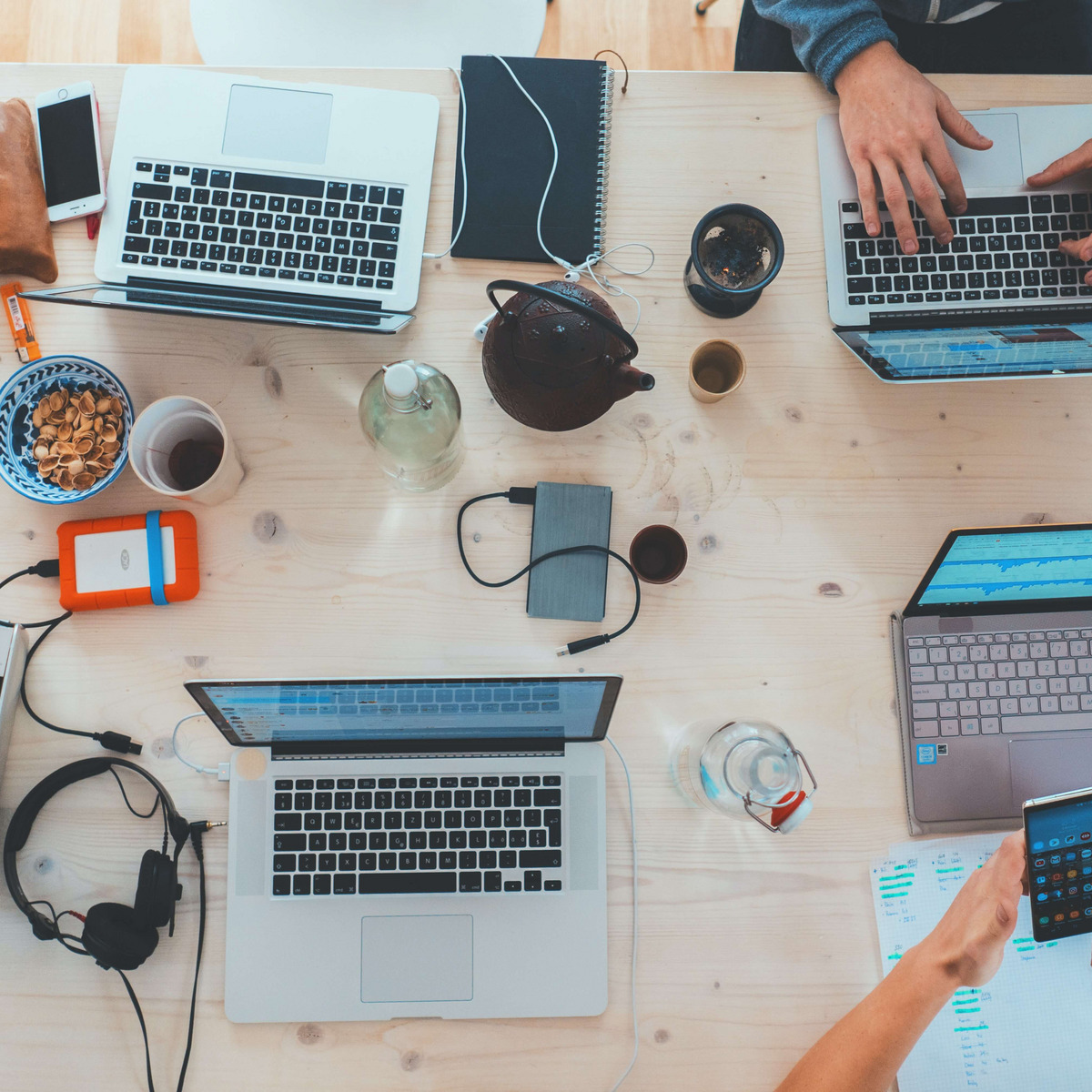 Tisch auf dem Laptops, externe Festplatten, Schreibutensilien, Snacks und Tee stehen