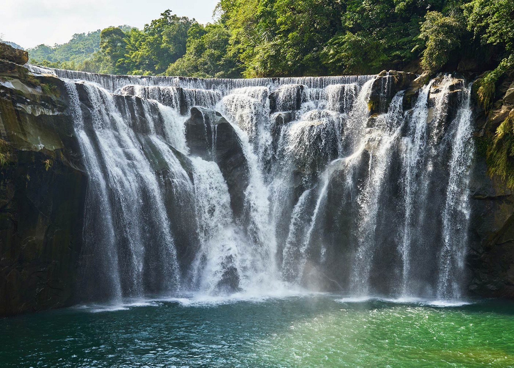 Ein mächtiger Wasserfall inmitten eines sattgrünen Regenwaldes.