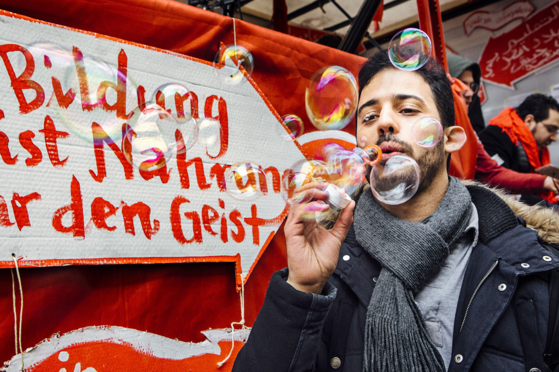 Ein Mann macht Seifenblasen vor einem Plakat mit den Worten "Bildung ist Nahrung für den Geist"