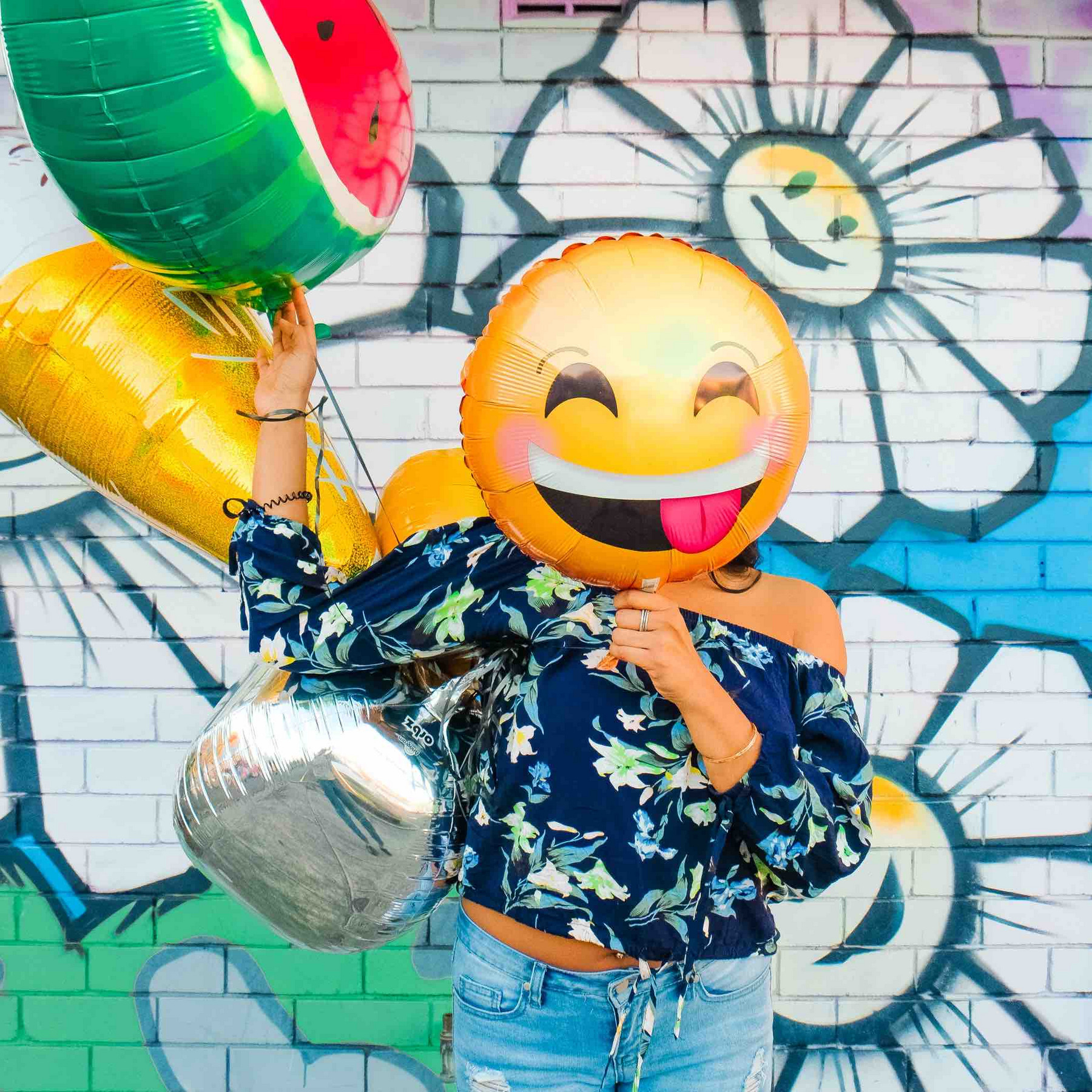 Eine Person mit einem Smiley-Luftballon vor dem Gesicht