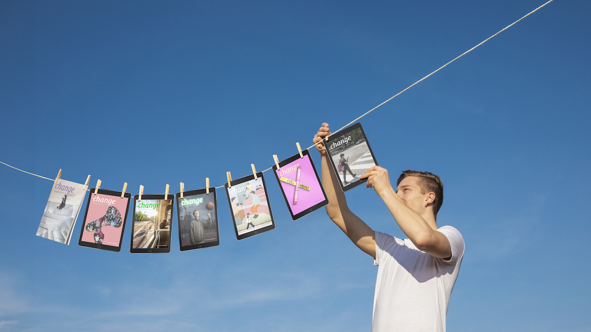 Vor blauem Himmel hängt eine Person in einem weißen T-Shirt verschiedene Ausgaben des 'change'-Magazins an eine Wäscheleine. Die Magazine sind mit Holzwäscheklammern befestigt und zeigen unterschiedliche Cover-Designs in verschiedenen Farben.