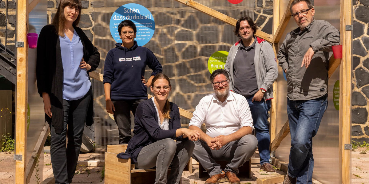 Das Foto zeigt sechs Personen, die für ein Gruppenfoto posieren. Es handelt sich um Teilnehmer:innen des "Summer of Pioneers", ganz links außen steht Sarah Ackermann.