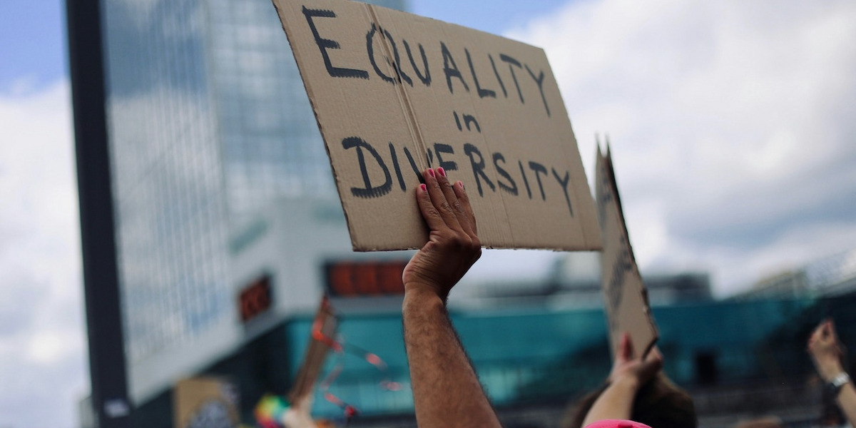 Auf einer Demonstration hält eine Hand ein Pappschild mit der Aufschrift „Equality in Diversity“ hoch