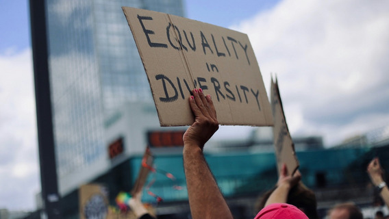 Auf einer Demonstration hält eine Hand ein Pappschild mit der Aufschrift „Equality in Diversity“ hoch