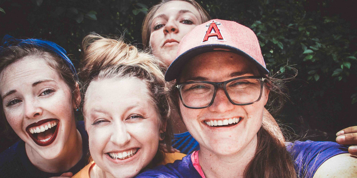 Vier junge Frauen schauen lachend in die Kamera.