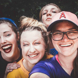 Vier junge Frauen schauen lachend in die Kamera.