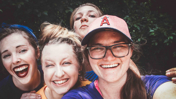 Vier junge Frauen schauen lachend in die Kamera.