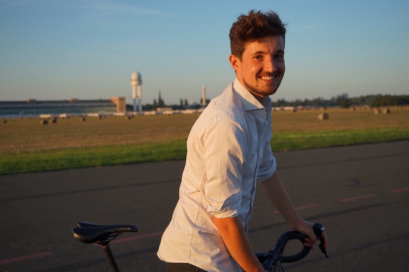 Ingwar Perowanowitsch mit einem Fahrrad während er in die Kamera lächelt.