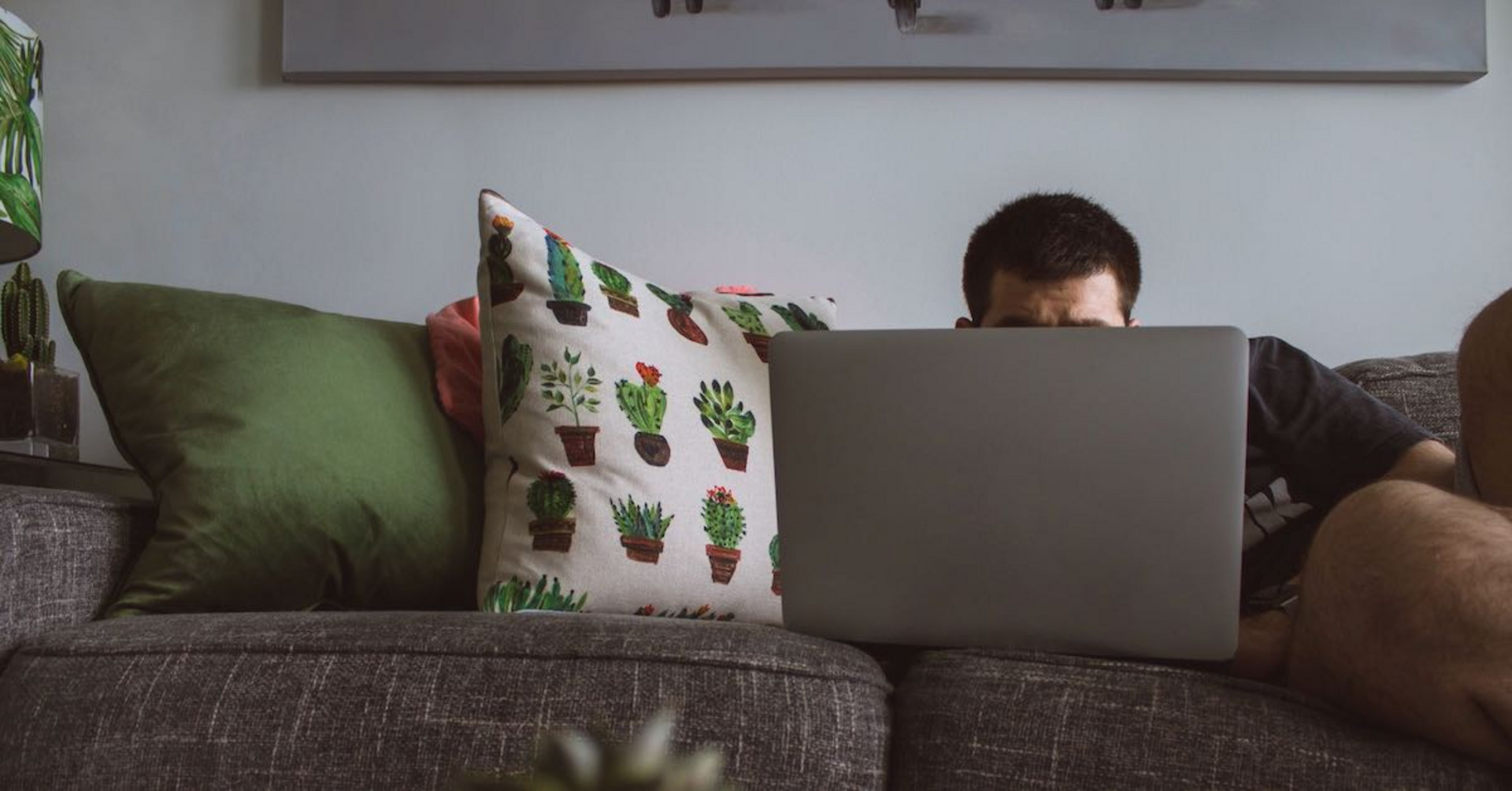 Ein Mann liegt auf der Couch vor seinem Computer.