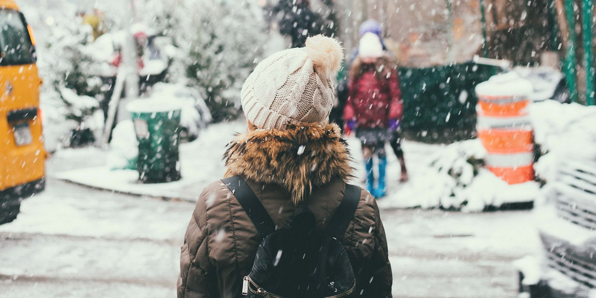 Es ist Winter und eine Frau wartet darauf, die Straße zu überqueren.