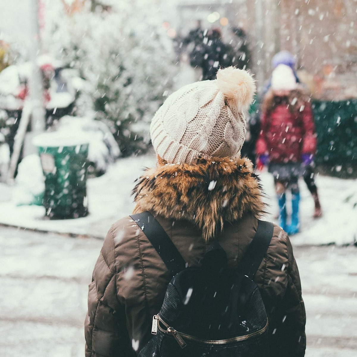 Es ist Winter und eine Frau wartet darauf, die Straße zu überqueren.
