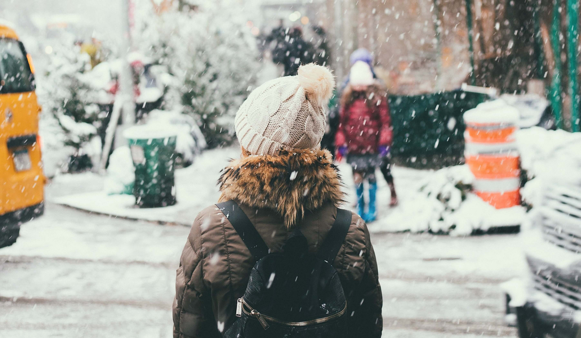 Es ist Winter und eine Frau wartet darauf, die Straße zu überqueren.