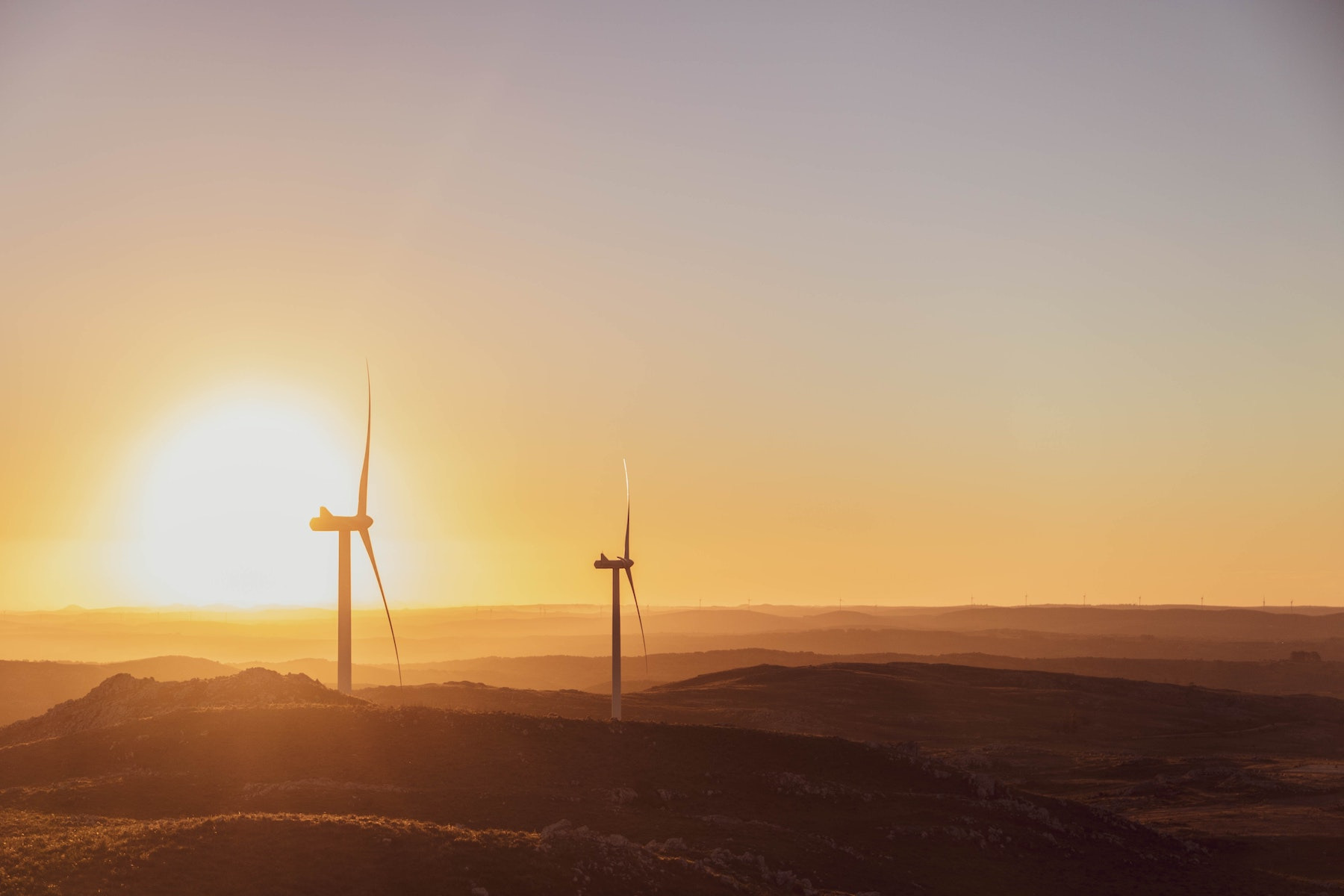 Zwei Windräder in einer Hügellandschaft nördlich von Maldonado im Sonnenuntergang.