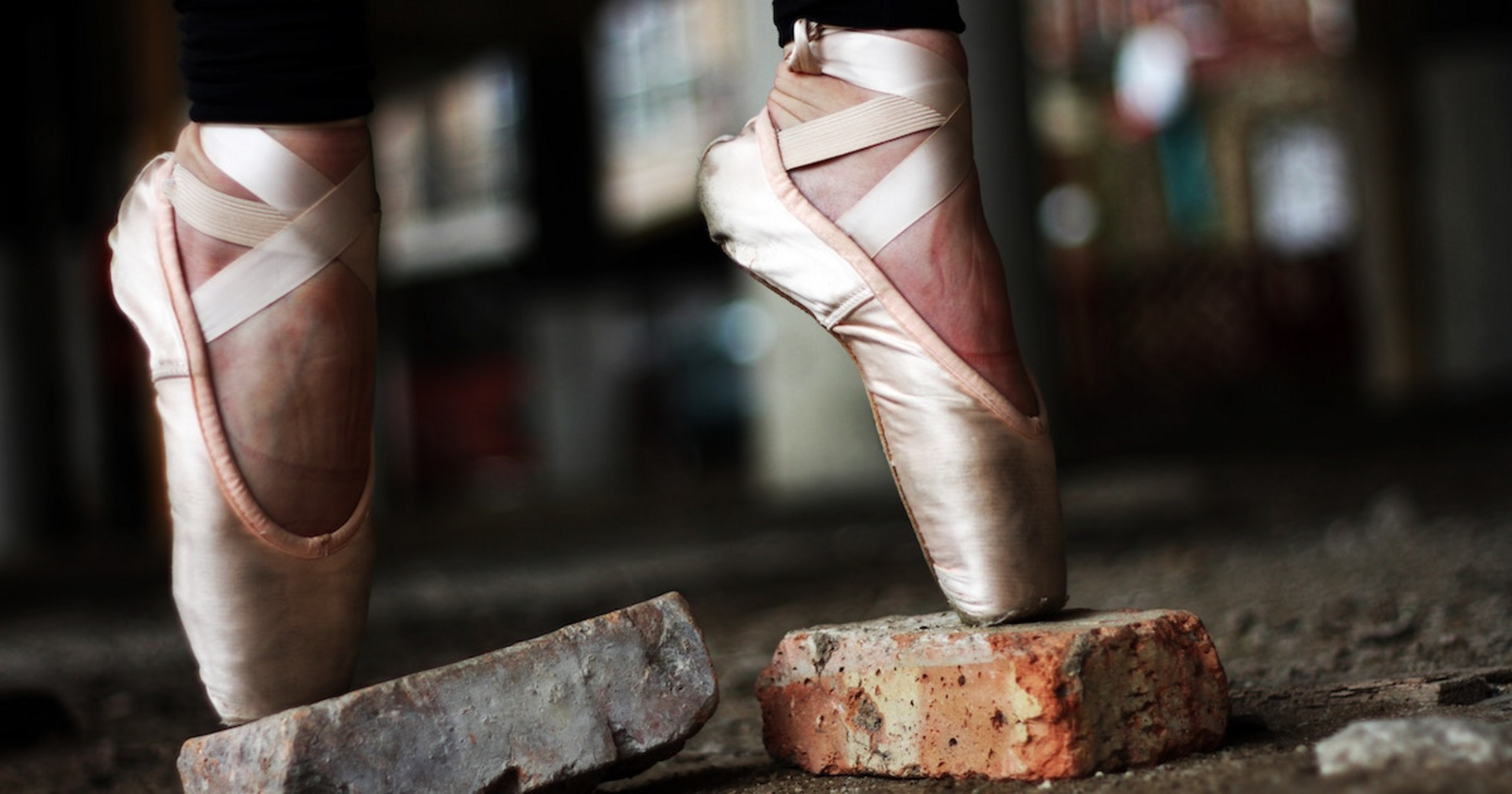 Person mit Ballettschuhen balanciert auf Ziegelsteinen