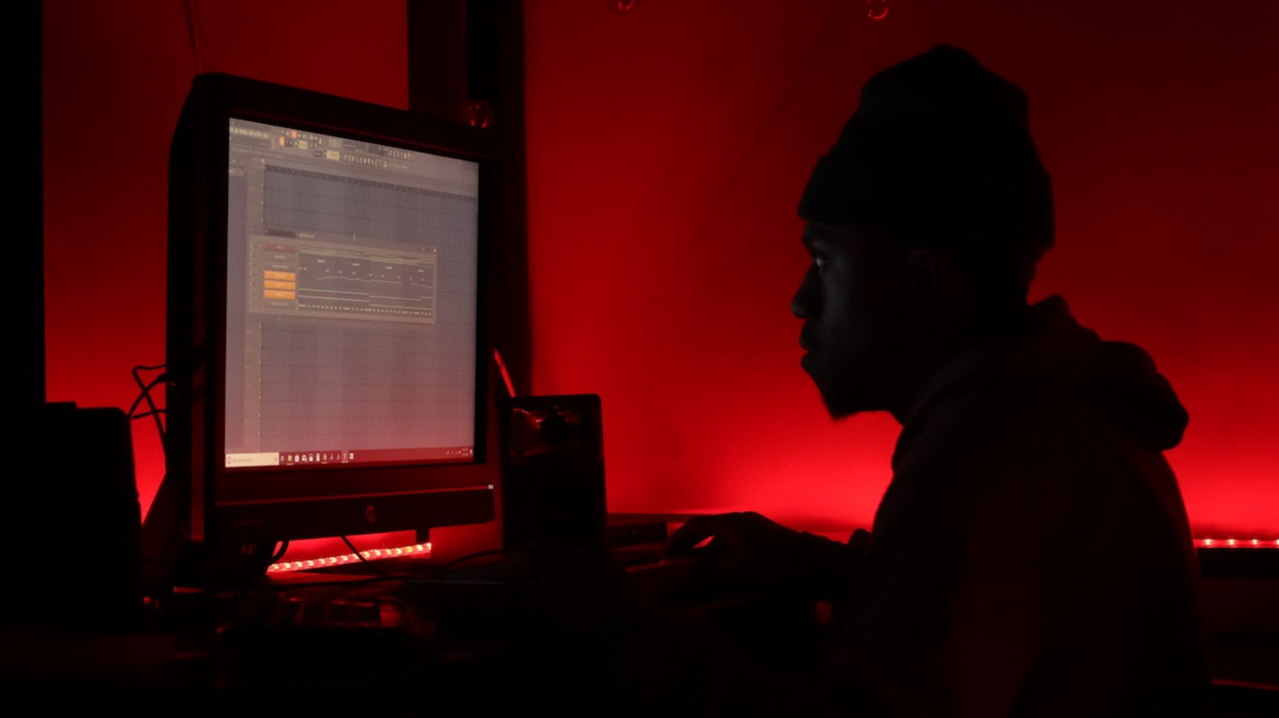 Eine Person sitzt vor einem Computer in einem Raum mit rotem Licht