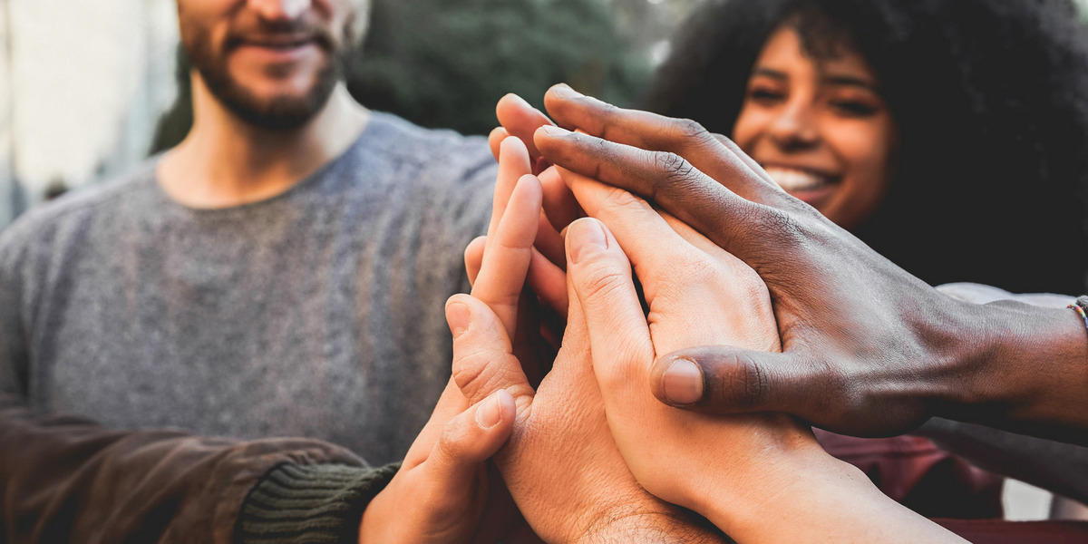 Menschen stehen im Kreis zusammen und geben High-Fives